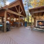 Large deck with hot tub, fireplace, and seating area