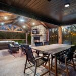 Outdoor dining area with gas fireplace overlooking creek