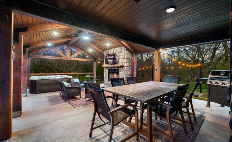 Outdoor dining area with gas fireplace overlooking creek