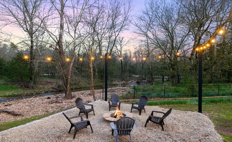 Firepit with string lights overlooking creek